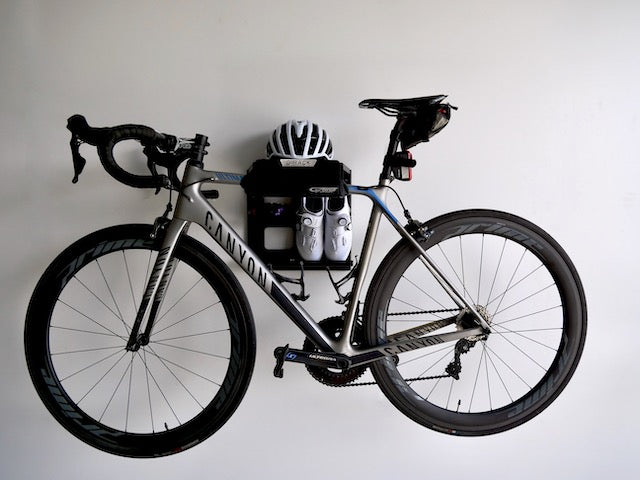 The G-Rack Model 2 - Wall Mounted Bike Rack holding a bicycle, helmet and shoes and mounted on a white wall