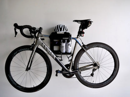 The G-Rack Model 2 - Wall Mounted Bike Rack holding a bicycle, helmet and shoes and mounted on a white wall