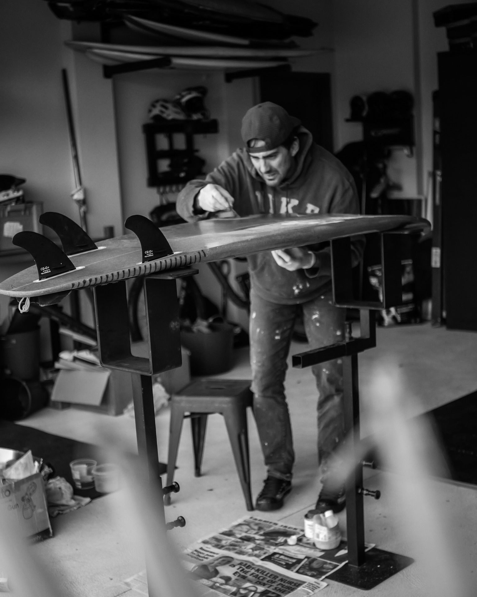 Man working on his surfboard in the garage, using the G-Force Adjustable Shaping Rack