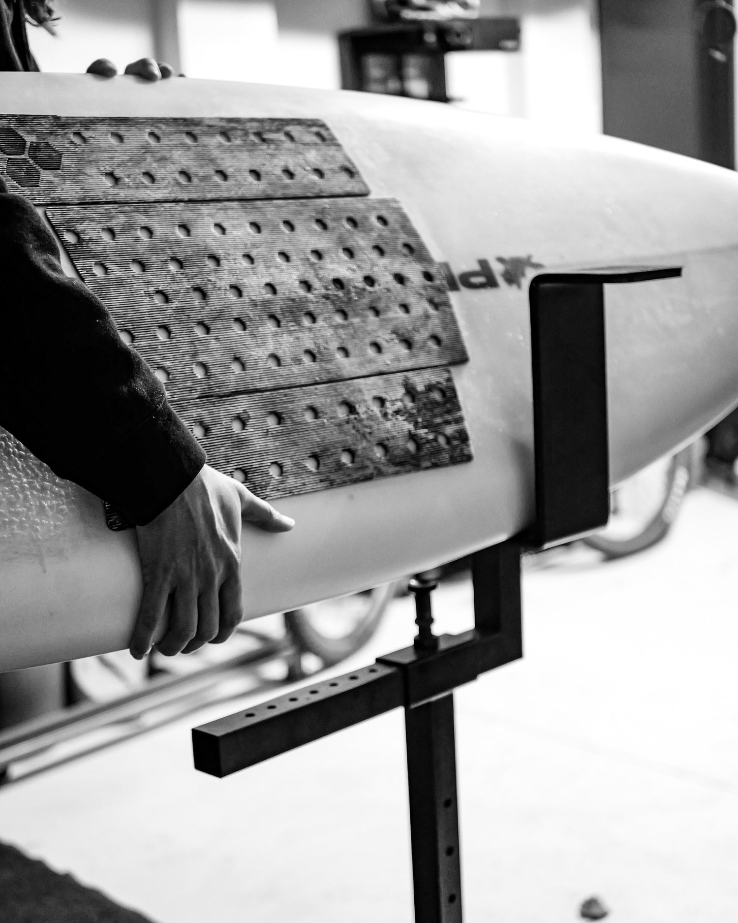 Person working on a surfboard with the G-Force Adjustable Shaping Rack