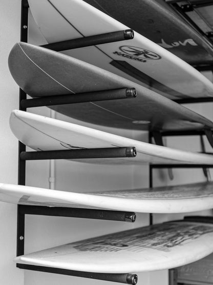 Stack of surfboards on a rack with a focus on the top two boards.